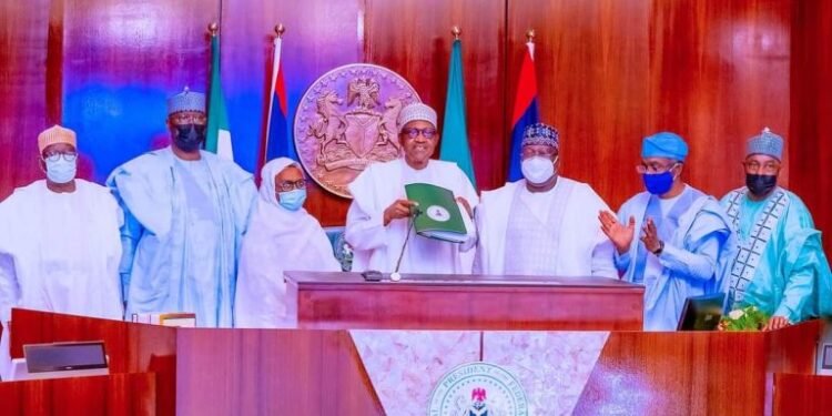 •President Muhammadu Buhari (m) displaying a copy of the signed Electoral Act 2022