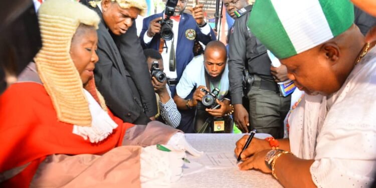 •Governor Ademola  Adeleke (r) signing the dotted lines after taking the Oath of Office administered on him the CJ of the state, Justice Adepele Ojo