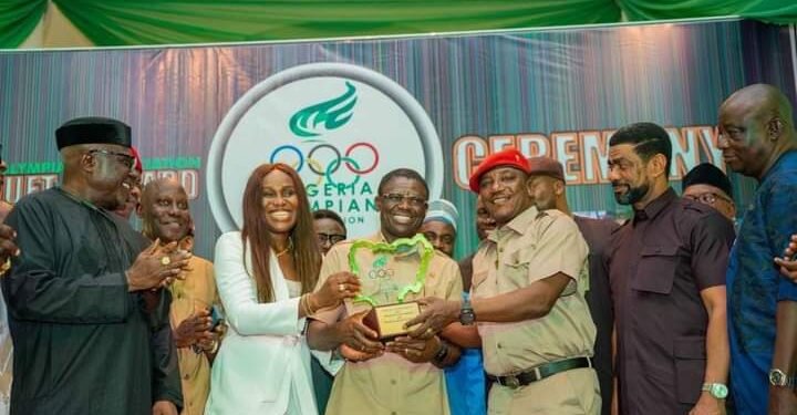 •Shaibu, flanked by his wife, Maryann; former Youth and Sports Minister, Solomon Daulung, and others, receives NOA's special recognition award in Abuja.