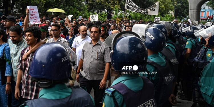 Activists walk past police personnel standing guard during a protest march demanding justice for victims arrested and killed in the recent countrywide violence in Dhaka on August 2, 2024. - Demonstrations in Bangladesh after August 2 prayers demanded justice for victims of nationwide unrest and police crackdown, after the release of protest leaders failed to quell public anger. (Photo by Munir UZ ZAMAN / AFP)